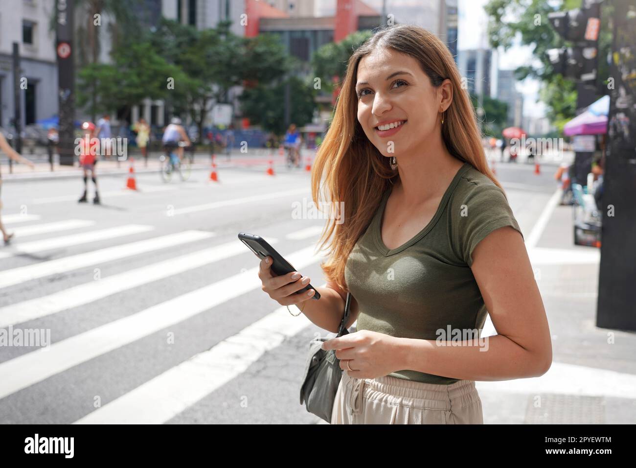 Femme brésilienne utilisant un smartphone regardant loin sur Paulista Avenue, Sao Paulo, Brésil Banque D'Images