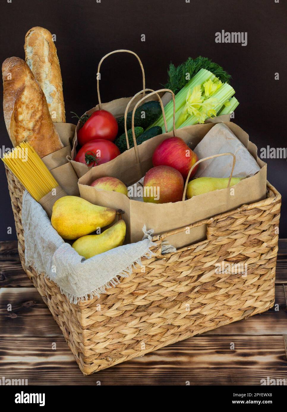 Légumes frais, légumes verts et fruits, céréales et pâtes dans un panier en osier. Livraison ou don de concept alimentaire. Banque D'Images