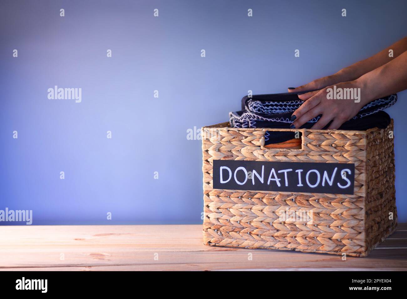Mains mettant une couverture dans une boîte pour les dons de vêtements sur  un fond bleu. Concept de charité et de don. Espace de copie Photo Stock -  Alamy