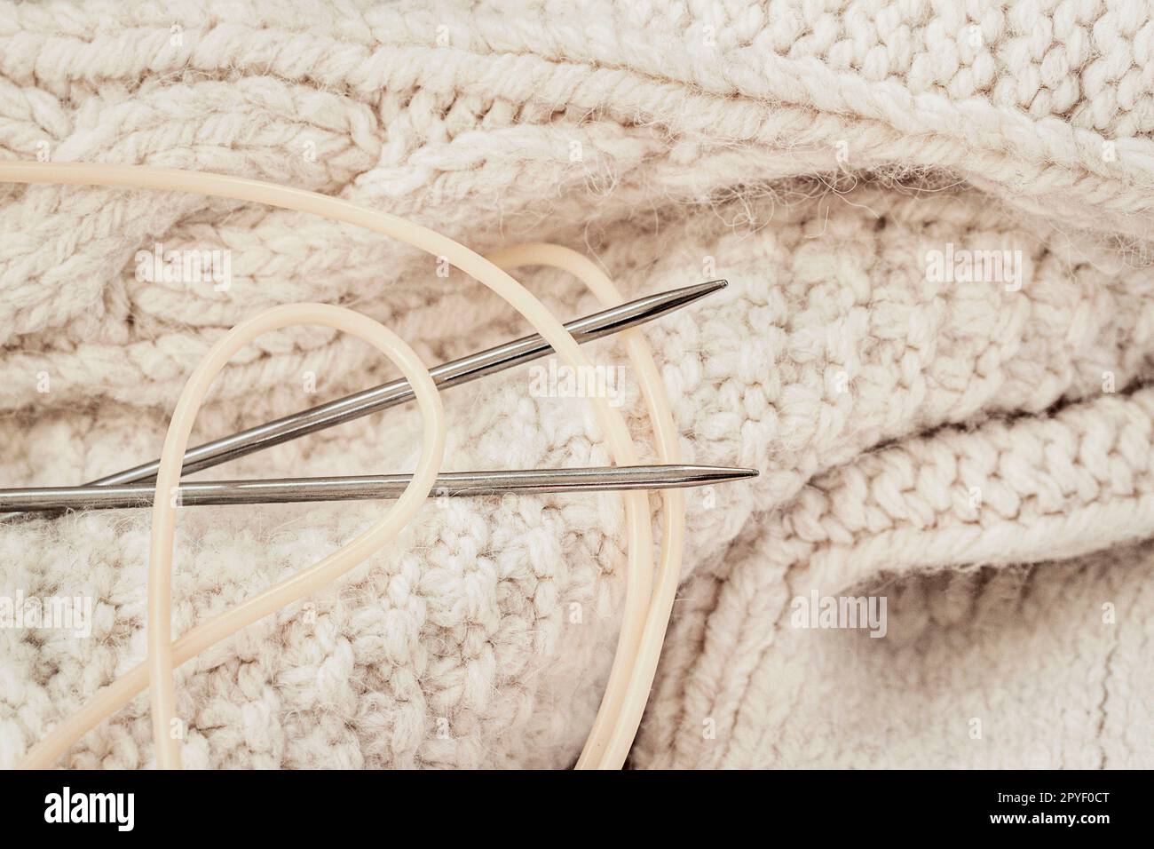 Gros plan du pull en fil blanc tricoté, aiguille tricotée. Tricotage, passe-temps, concept d'artisanat Banque D'Images