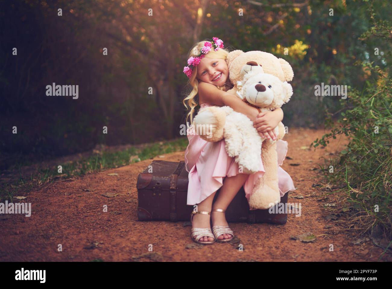 Je suis heureux tant qu'ils sont là. une petite fille heureuse assise et attendant avec ses ours en peluche au milieu d'une route de terre. Banque D'Images