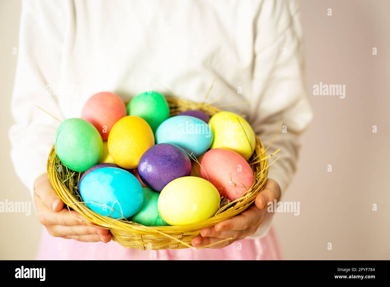 Une belle fille, de cinq ans, tenant un panier avec beaucoup d'oeufs de Pâques colorés dans ses mains. Banque D'Images