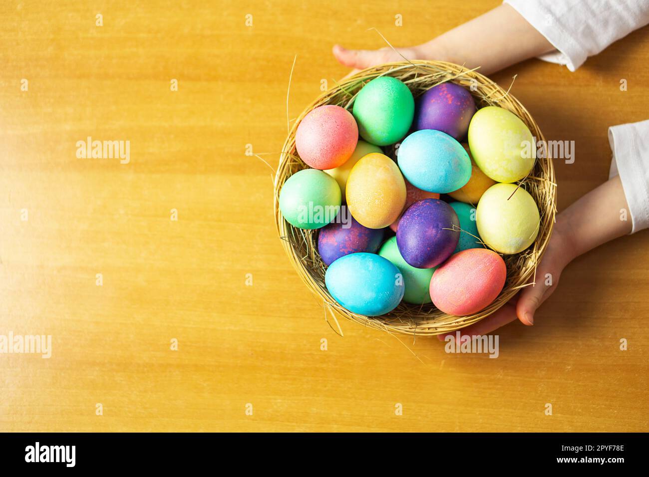 Une fille, de cinq ans, tenant un panier avec de nombreux oeufs de Pâques colorés dans ses mains. Banque D'Images