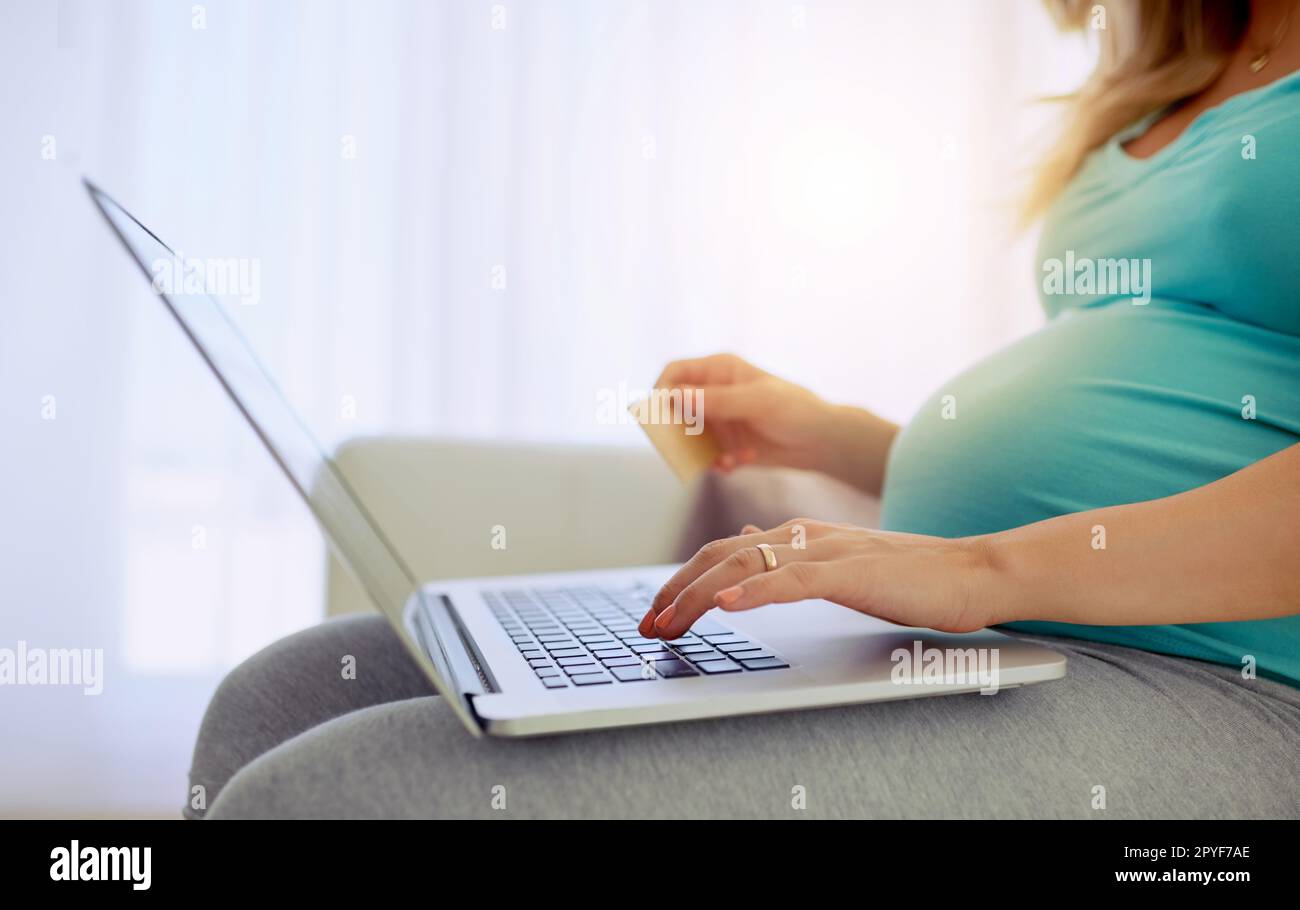 Shopping dans le confort. Gros plan d'une femme enceinte faisant quelques achats en ligne à la maison. Banque D'Images
