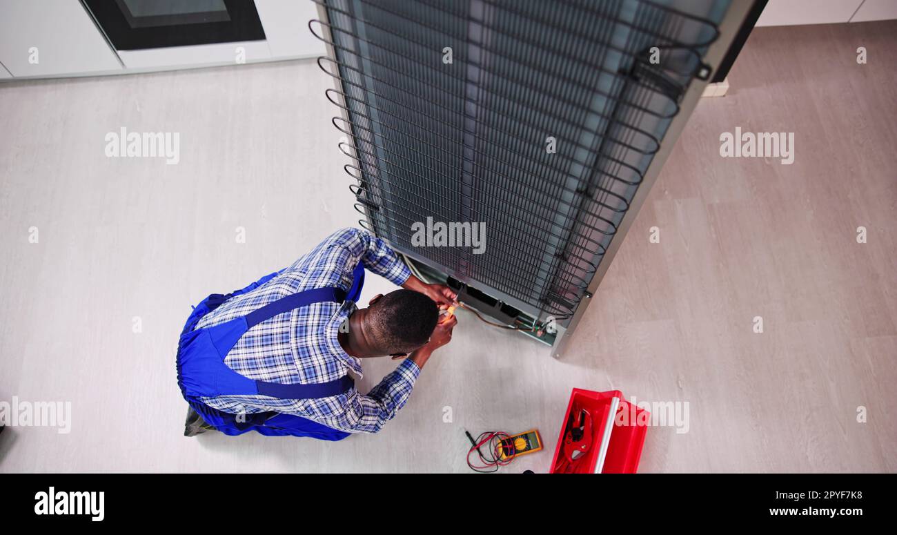 Jeune homme technicien travaillant sur le réfrigérateur avec tournevis Banque D'Images