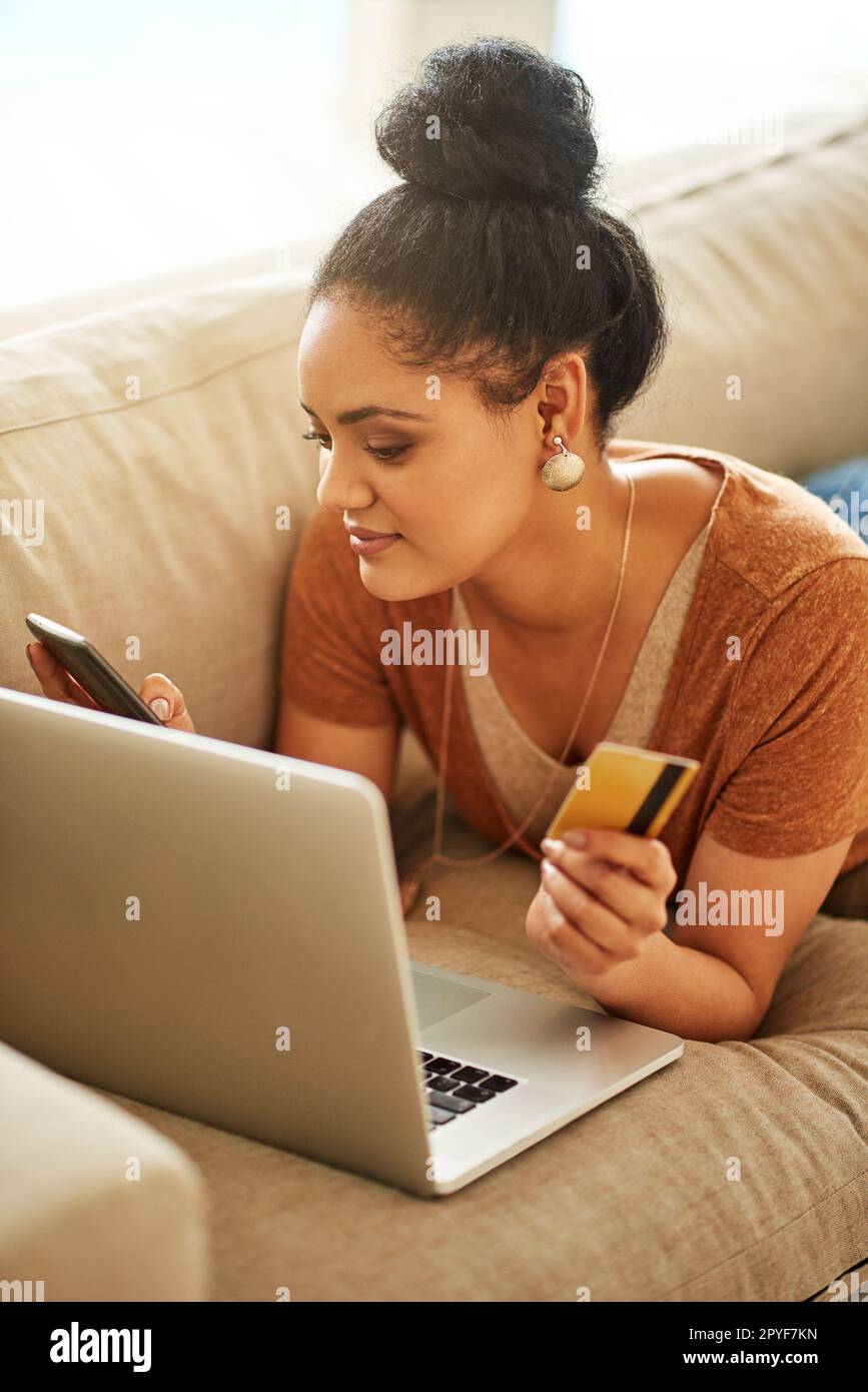 La réservation en ligne peut être une tâche confortable et pratique. une belle jeune femme utilisant un ordinateur portable et une carte de crédit à la maison. Banque D'Images