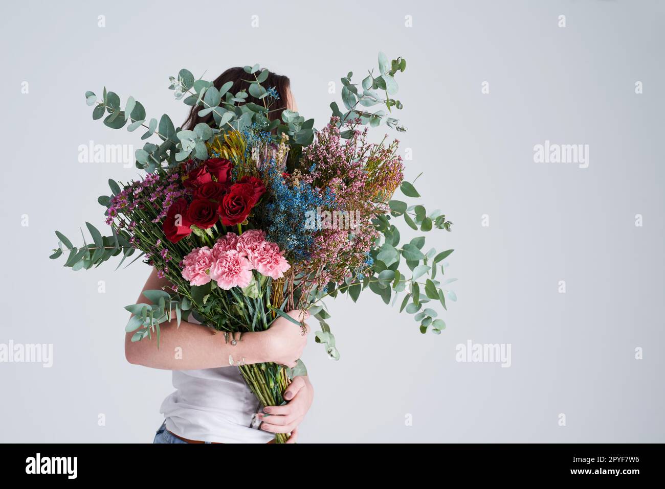 Il n'y a rien de plus beau qu'un bouquet. Photo en studio d'une femme méconnue tenant des fleurs sur un fond gris. Banque D'Images