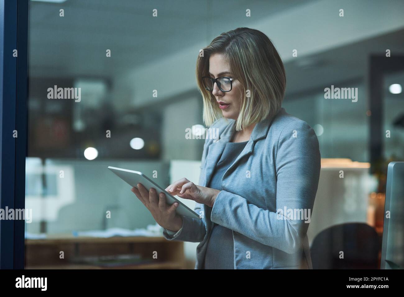 Travailler plus intelligemment, pas plus dur. une femme d'affaires travaillant sur une tablette numérique dans son bureau tard dans la nuit. Banque D'Images