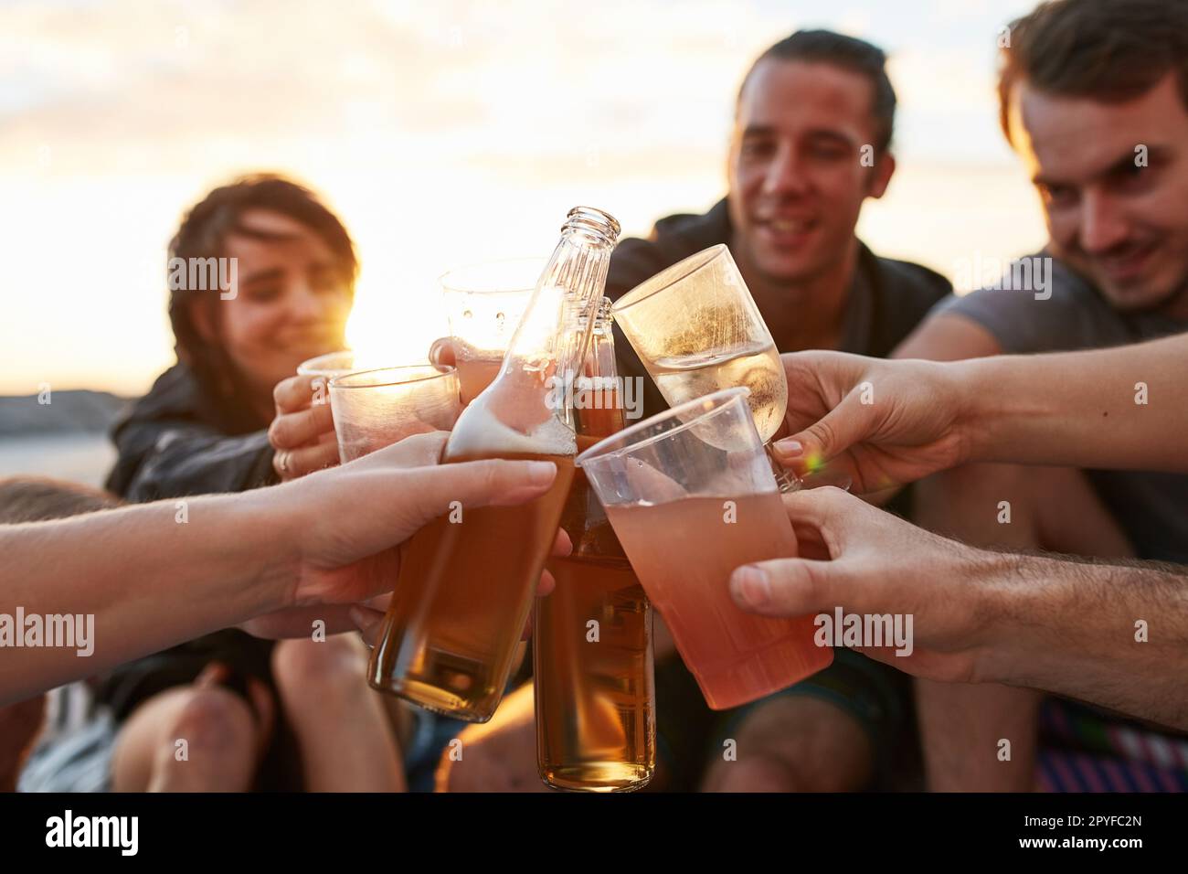 Heres au meilleur été jamais. un groupe de jeunes amis heureux en dégustant leurs boissons tout en se relaxant sur la plage. Banque D'Images