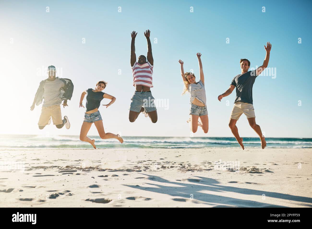 Woop Woop Summer break est là. un groupe de jeunes amis sautant avec enthousiasme dans les airs à la plage. Banque D'Images
