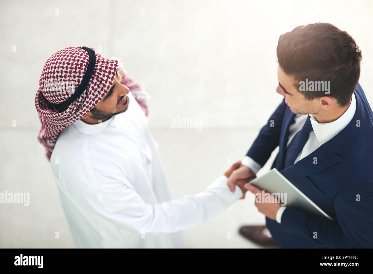 La mise en réseau à des millions. un jeune homme d'affaires musulman qui se tremble avec un associé dans un bureau moderne. Banque D'Images