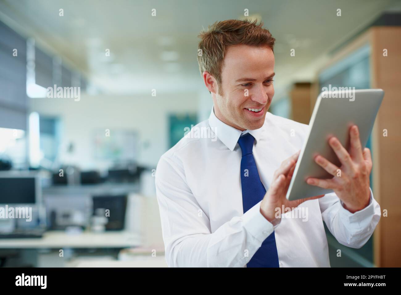 Émerveillé par cette technologie tactile. Jeune homme d'affaires utilisant un pavé numérique pendant qu'il est au bureau. Banque D'Images