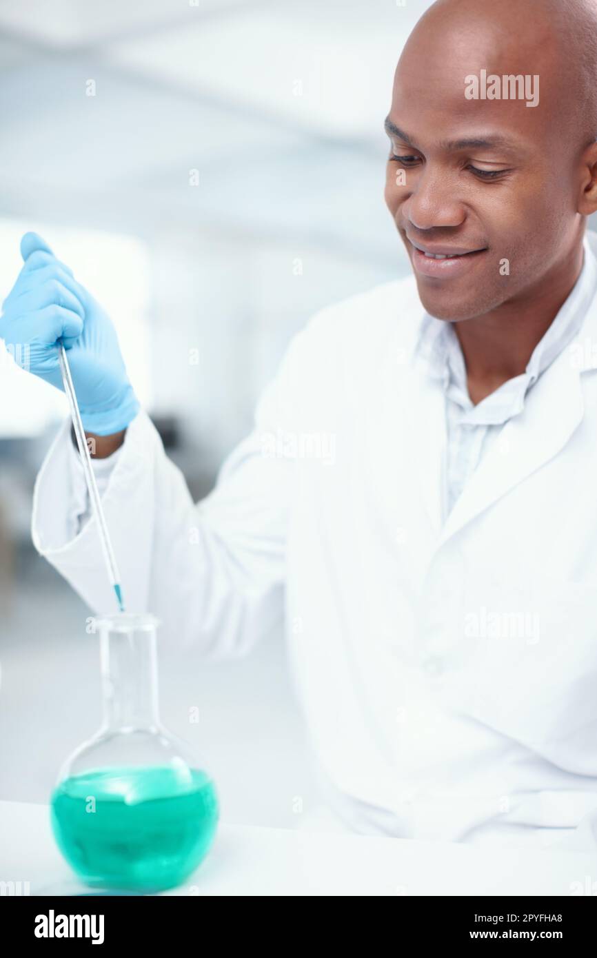 Juste la bonne quantité de produits chimiques. Un scientifique masculin attrayant ajoutant un produit chimique à un autre dans le laboratoire. Banque D'Images