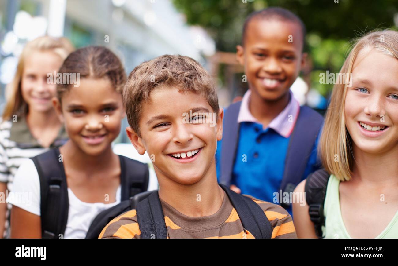 Construire de grandes amitiés à l'école. Groupe souriant d'enfants de différents groupes ethniques se posant à l'extérieur pour une image heureuse. Banque D'Images