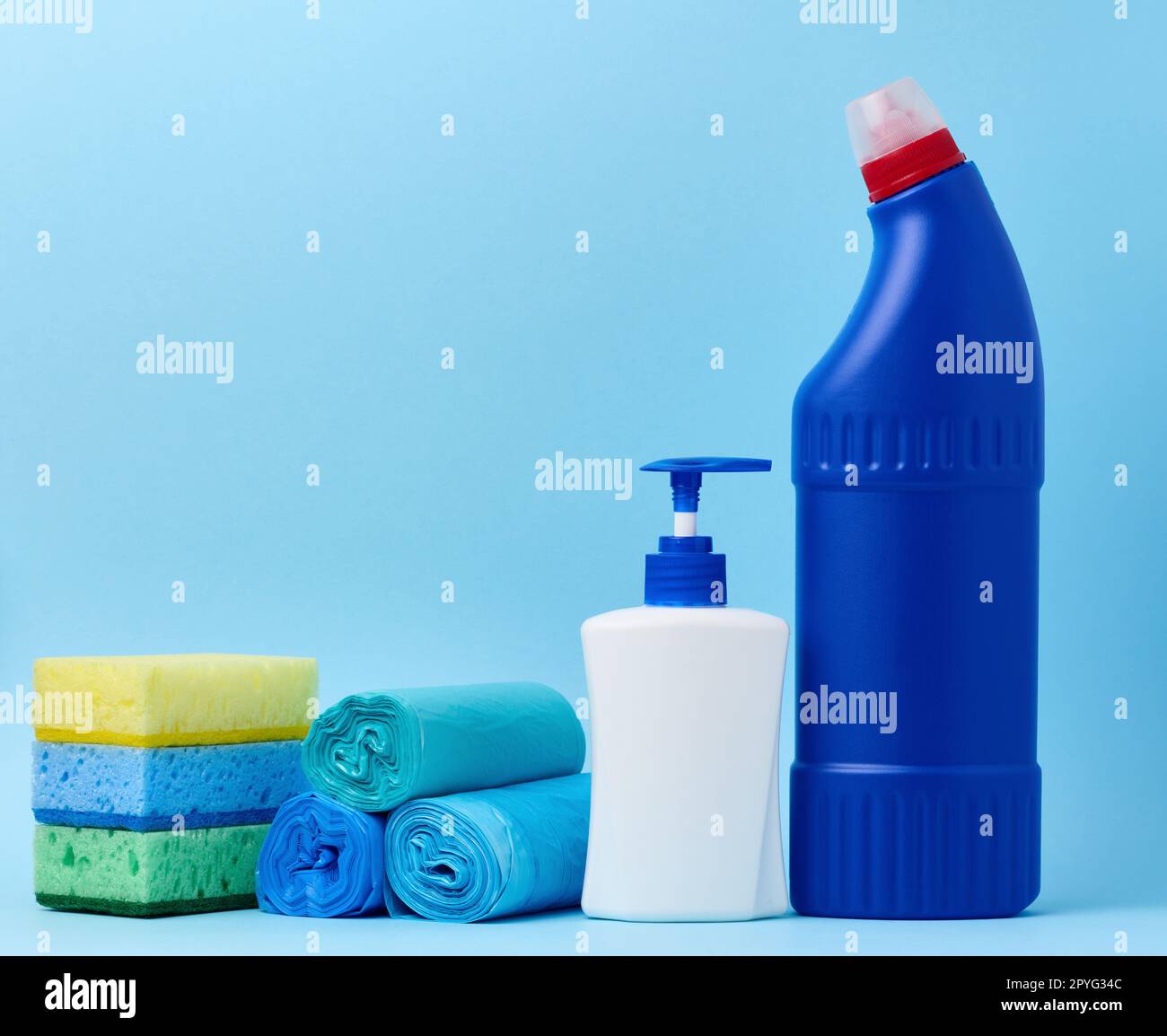 Bouteille en plastique blanc avec distributeur et sacs poubelle, éponges et bouteille bleue avec détergent sur fond bleu Banque D'Images