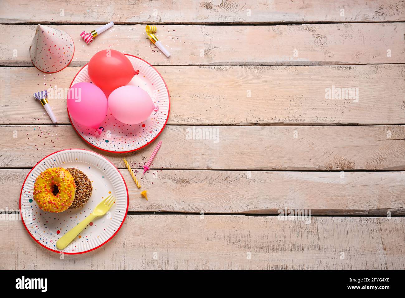 Assiettes jetables en papier avec beignets, ballons, chapeau de fête et  bougies sur fond de bois clair Photo Stock - Alamy