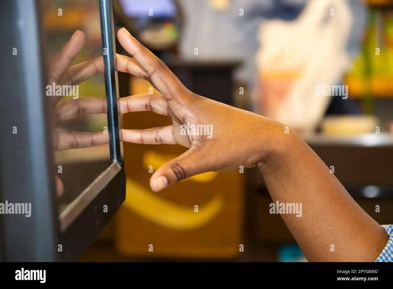 Main de fille noire caissière en utilisant l'écran tactile caisse avec arrière-plan flou bokeh - reflet de la main dans l'écran Banque D'Images