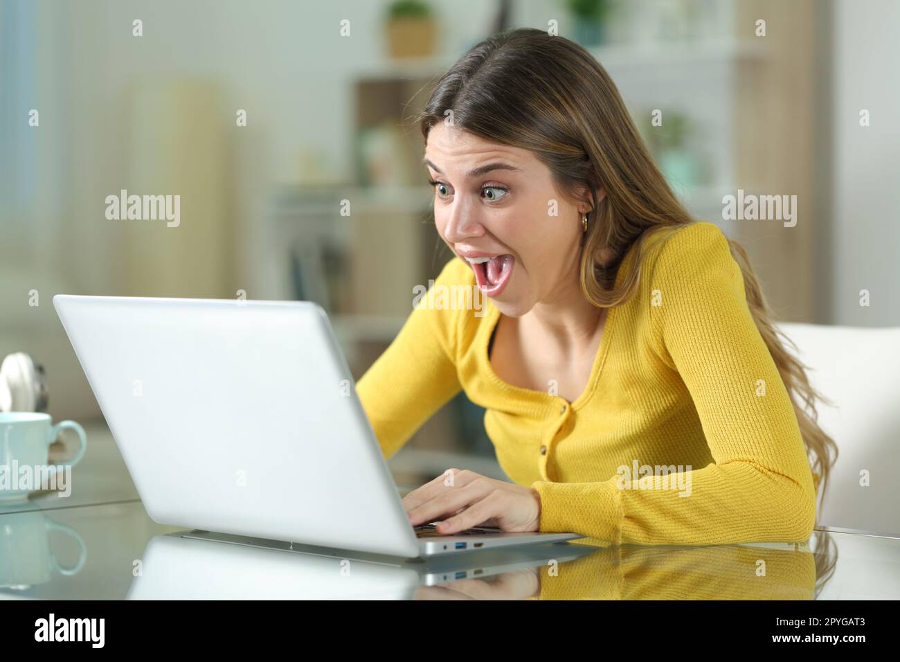 Femme étonné vérifiant le contenu de l'ordinateur portable à la maison Banque D'Images