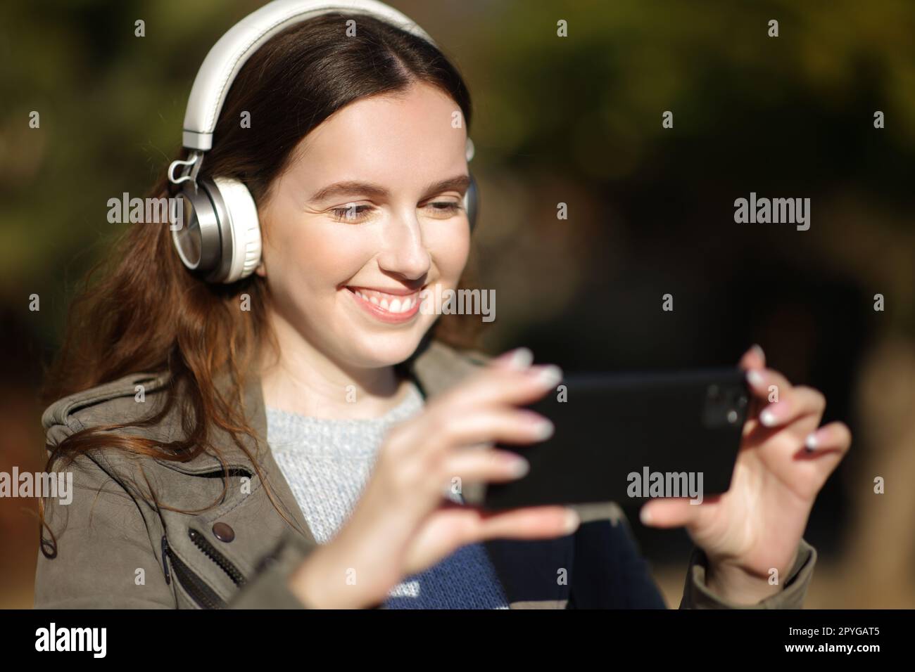 Femme heureuse regardant et écoutant la vidéo sur le téléphone Banque D'Images