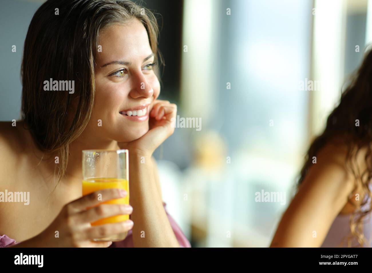 Femme heureuse tenant le verre de jus d'orange au petit déjeuner Banque D'Images