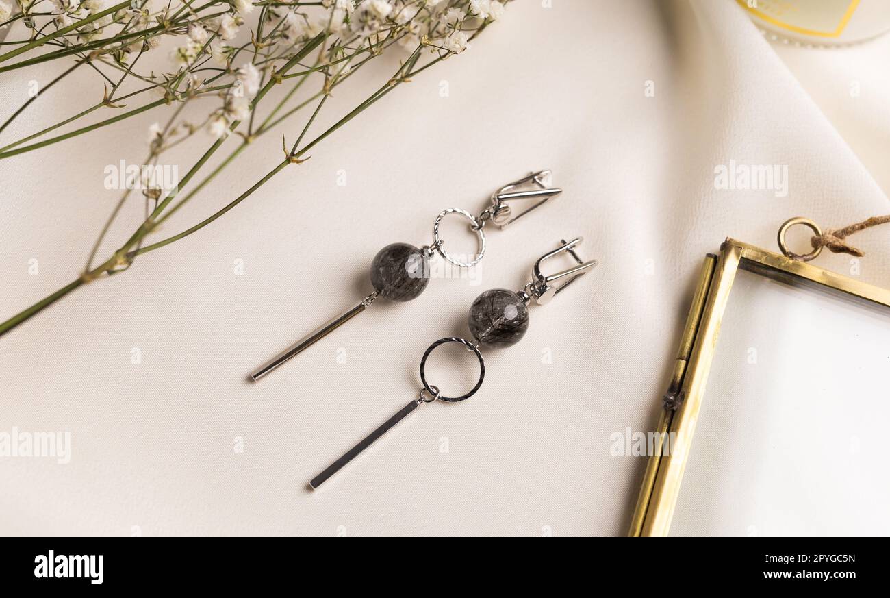 Ensemble de bijoux élégants de boucles d'oreilles argentées avec pierres précieuses. Ensemble de bijoux style minimaliste. Concept de bijouterie fait main. Banque D'Images