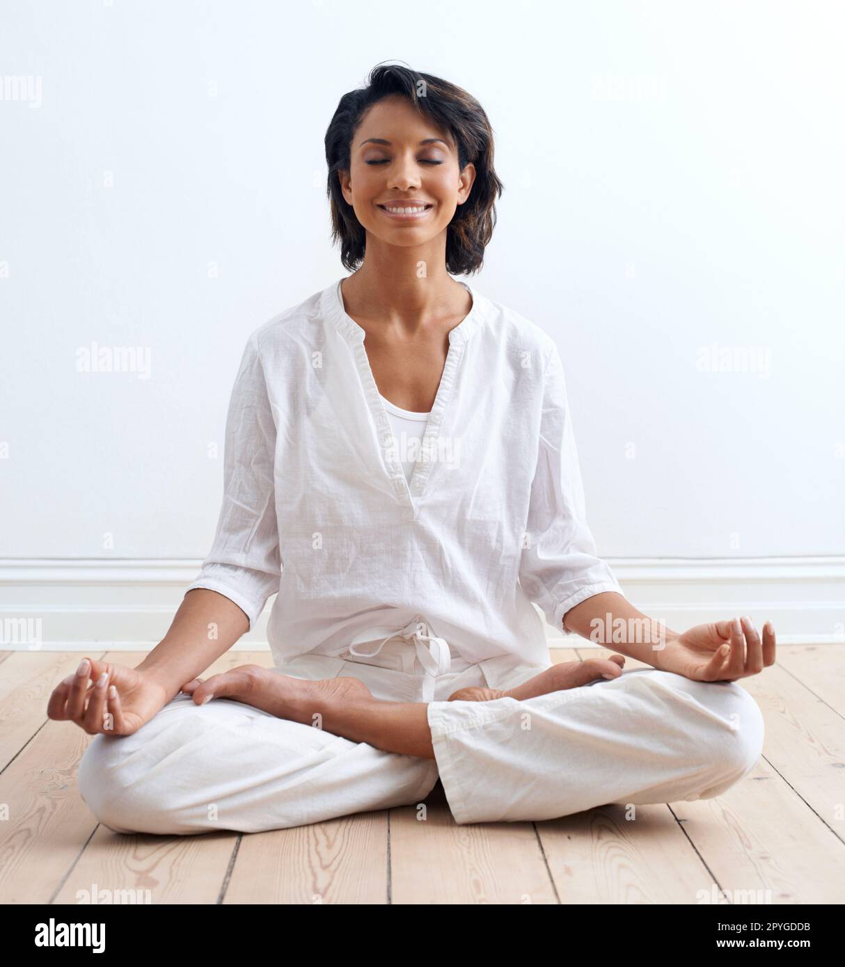 Aligner son esprit et son sentiment de paix. Une jeune femme content assise dans la position de lotus pendant sa routine de yoga. Banque D'Images