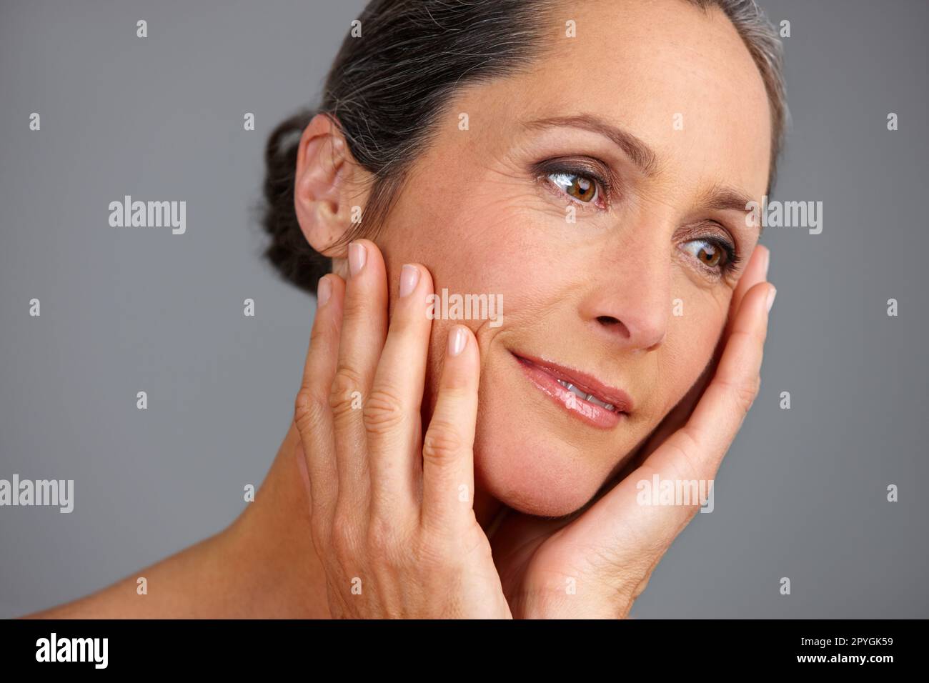 Beauté sans âge. Photo studio d'une belle femme mûre posant sur un fond gris. Banque D'Images