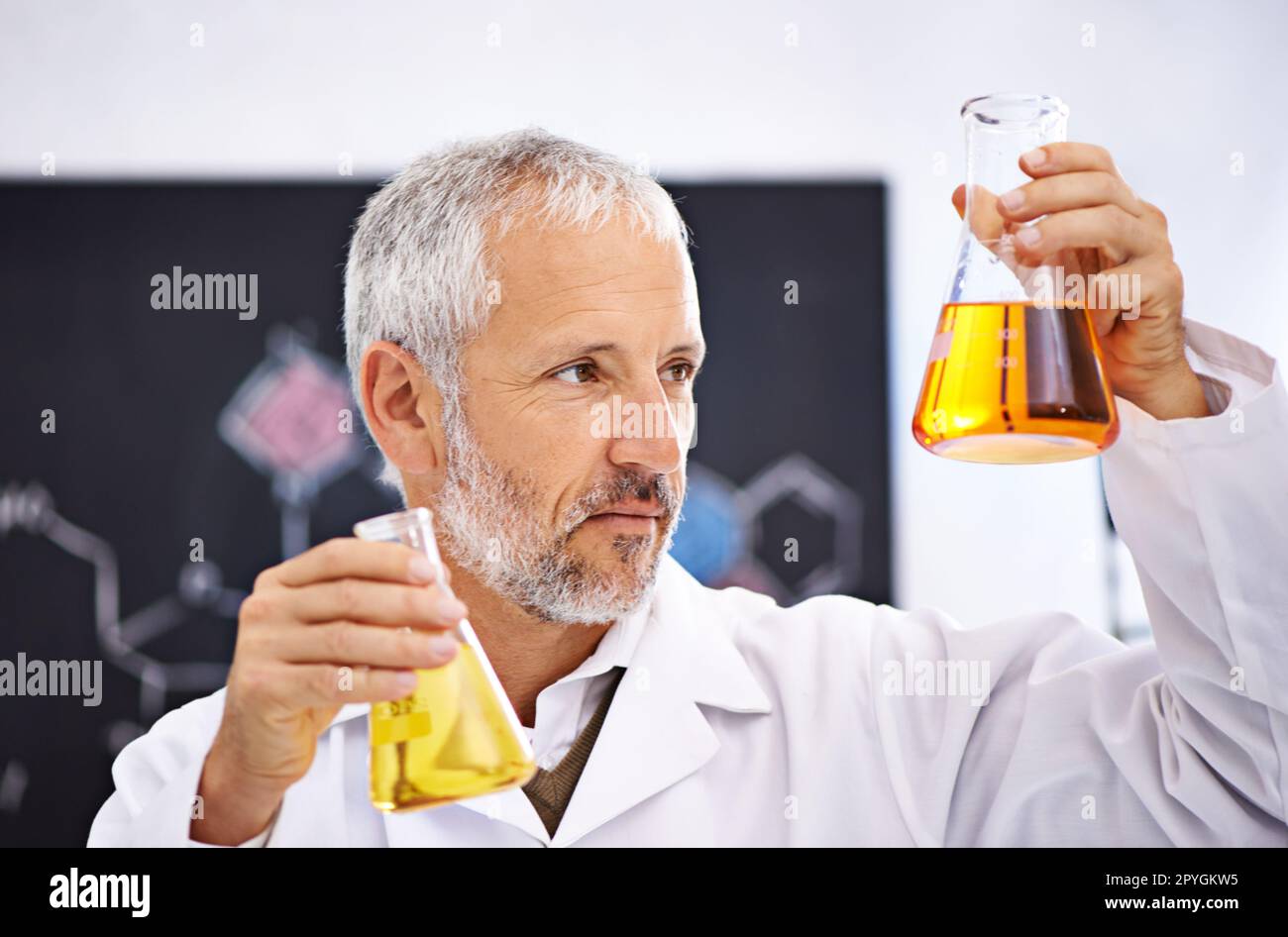 Observation des réactions chimiques en laboratoire. un scientifique mâle mature examinant les résultats d'une expérience dans son laboratoire. Banque D'Images