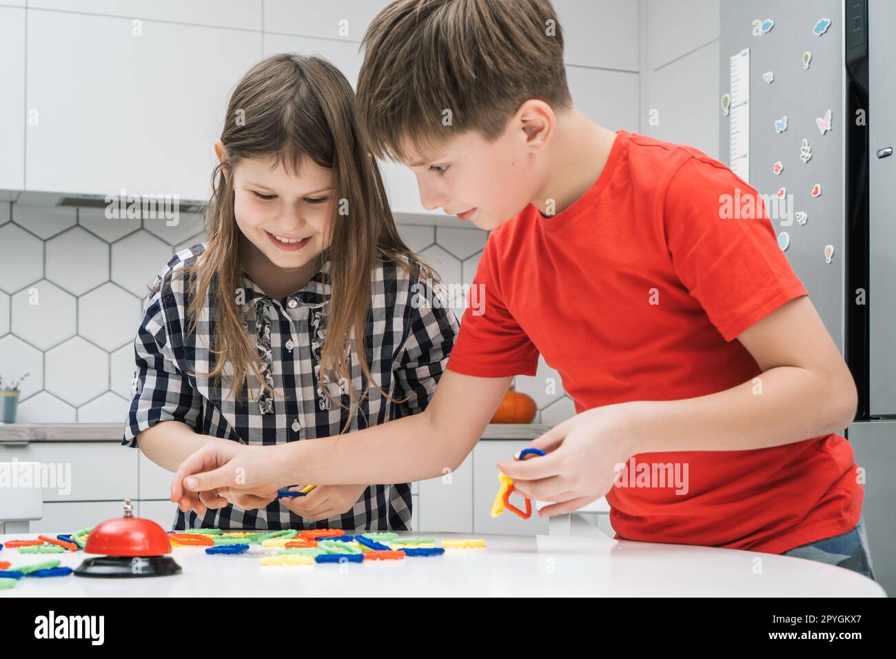 Rire, garçon drôle et fille jouent à un jeu de chaîne, reliant les pièces ensemble et faisant forme pour le temps. Créativité des enfants Banque D'Images