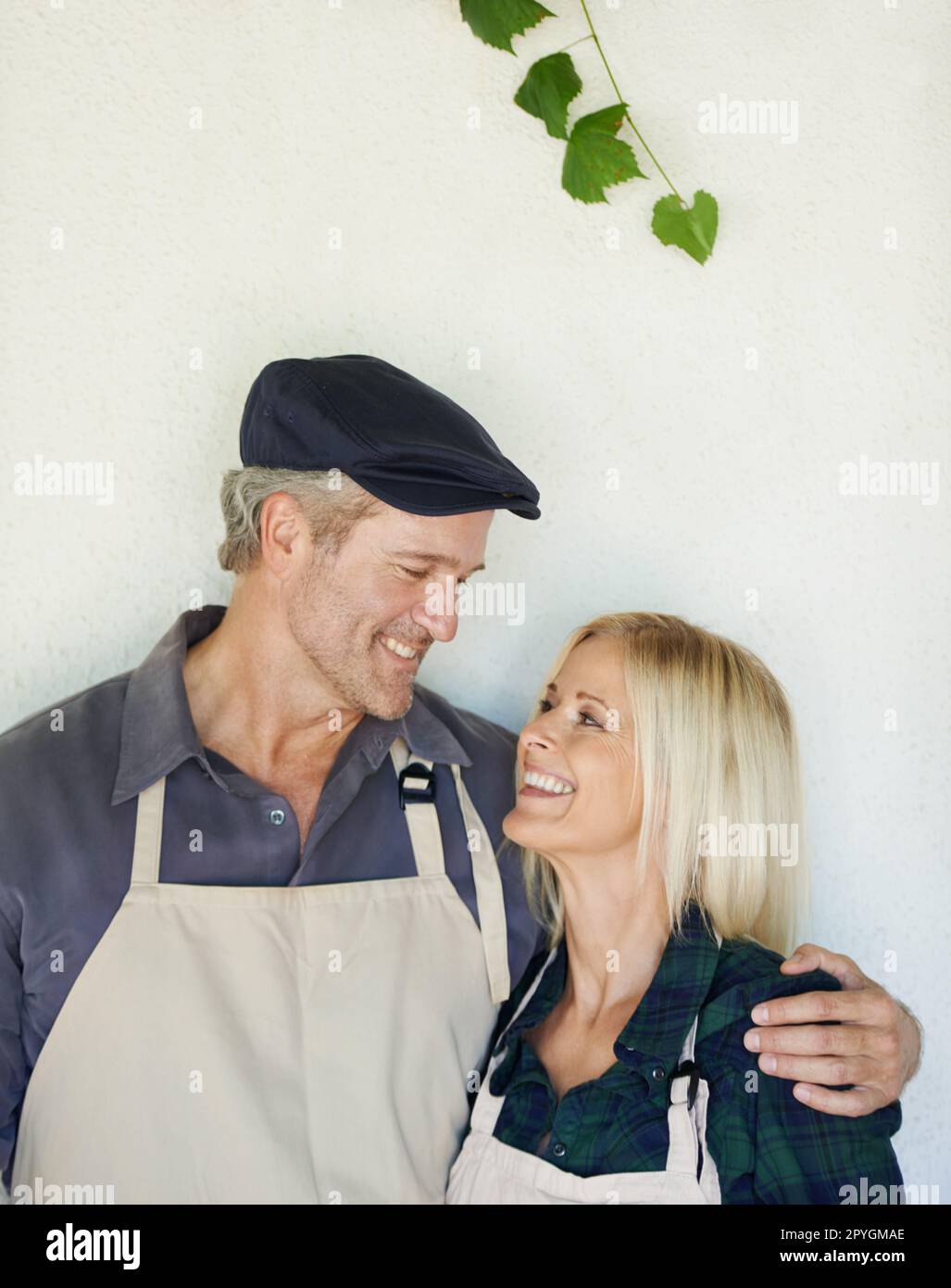 Ils aiment travailler ensemble. Un fermier et sa femme debout devant un mur. Banque D'Images