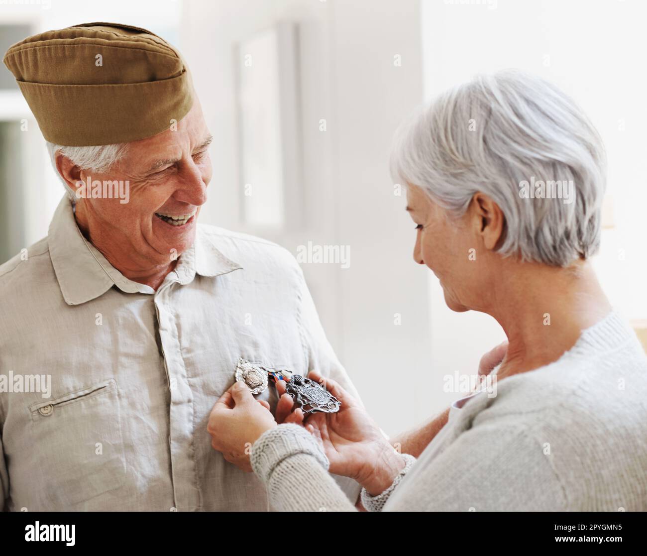 Je suis si fier de mon mari vétéran de la guerre. Une femme âgée qui regarde ses maris médailles alors qu'il porte l'uniforme complet de son armée. Banque D'Images