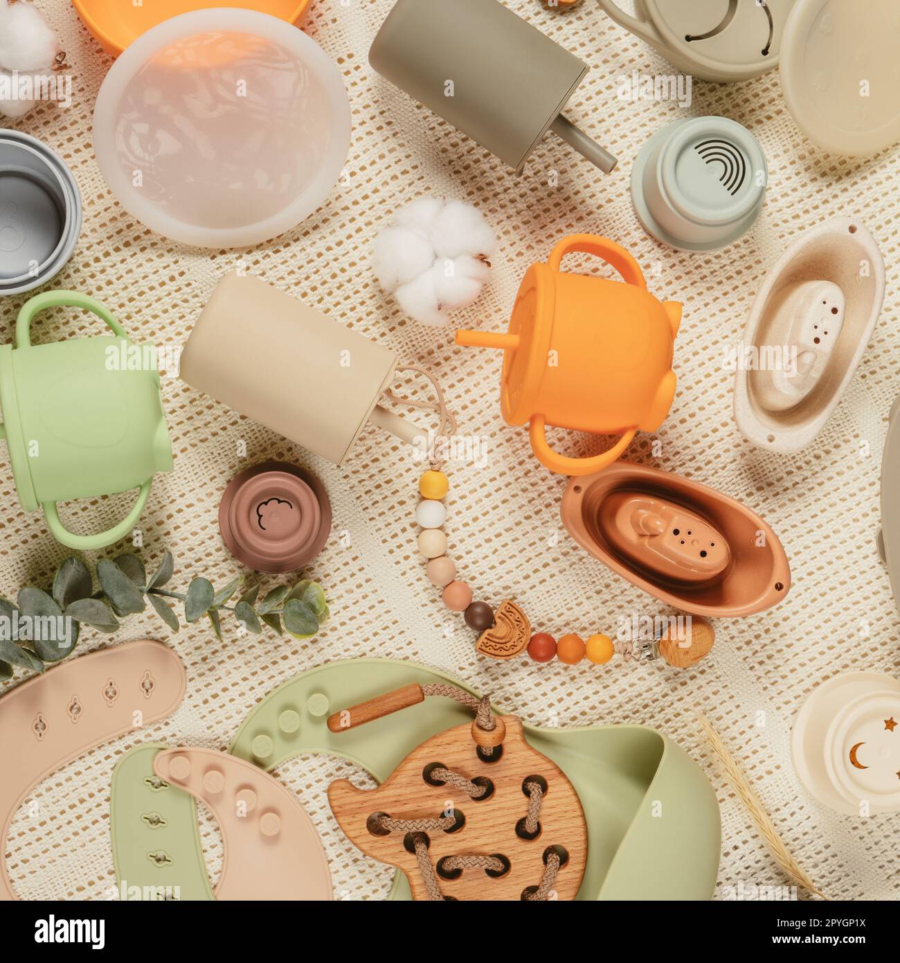 Collection silicone pastel de vaisselle, couverts, bavoirs, accessoires et jouets en bois pour enfants sur fond de tissu. Banque D'Images