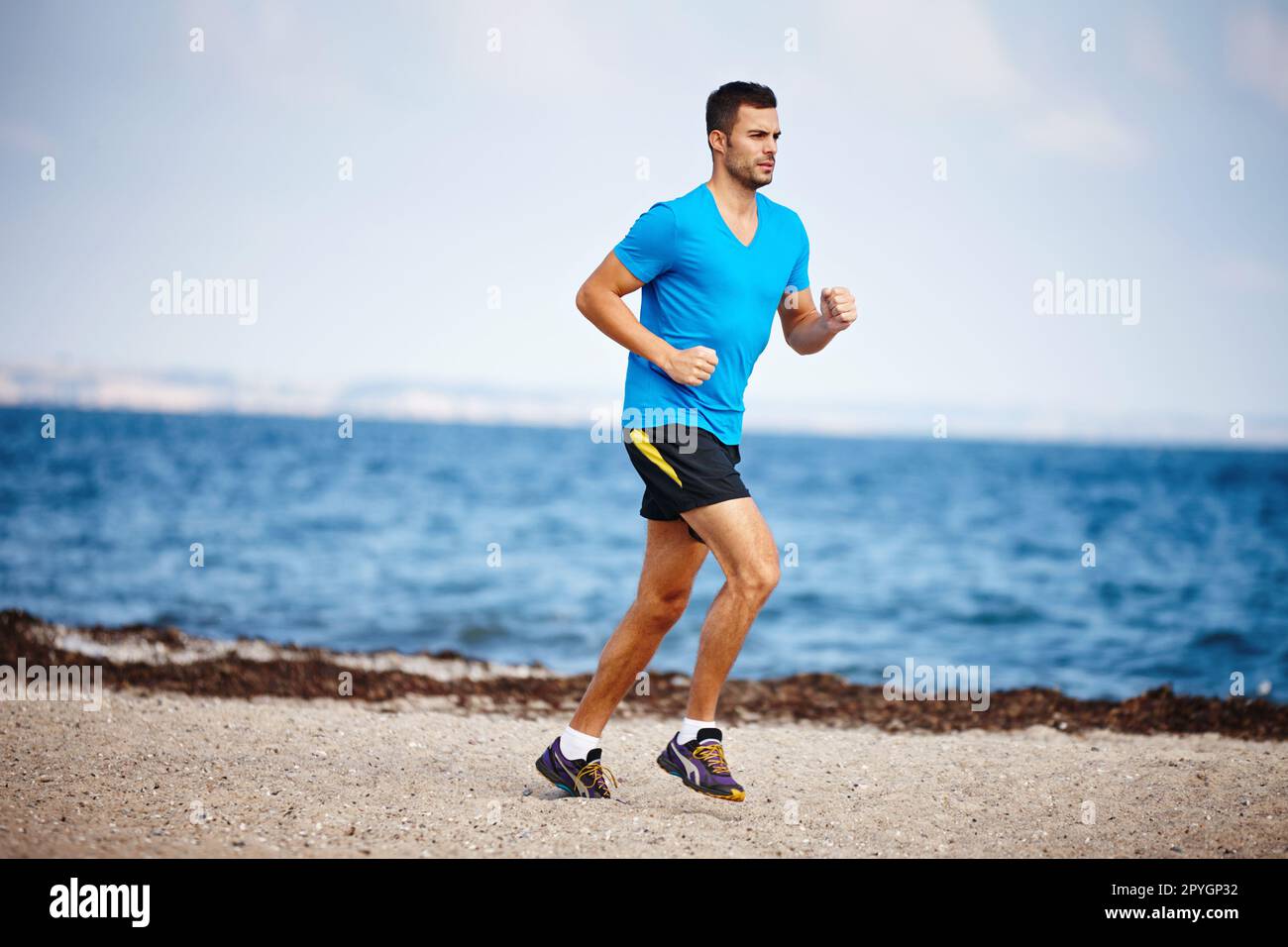 Courir avec vue sur l'océan. un beau jeune homme qui court sur la plage. Banque D'Images