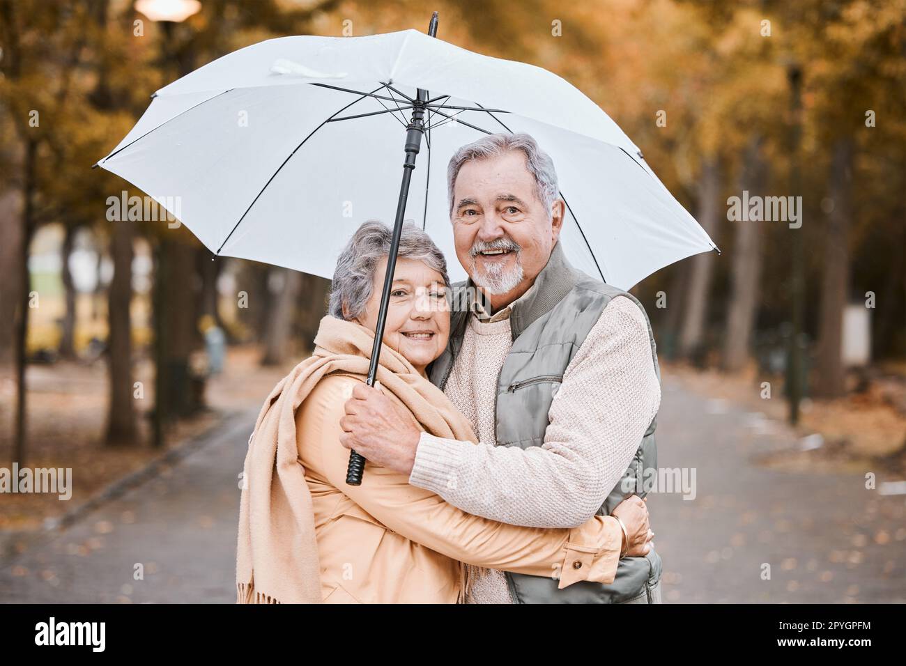 Hiver, câlin et couple aîné dans un parc, date de retraite et marche au Canada avec un parapluie. Nature affection, sourire et portrait d'un homme et d'une femme âgés en marche pour le bonheur et l'amour Banque D'Images