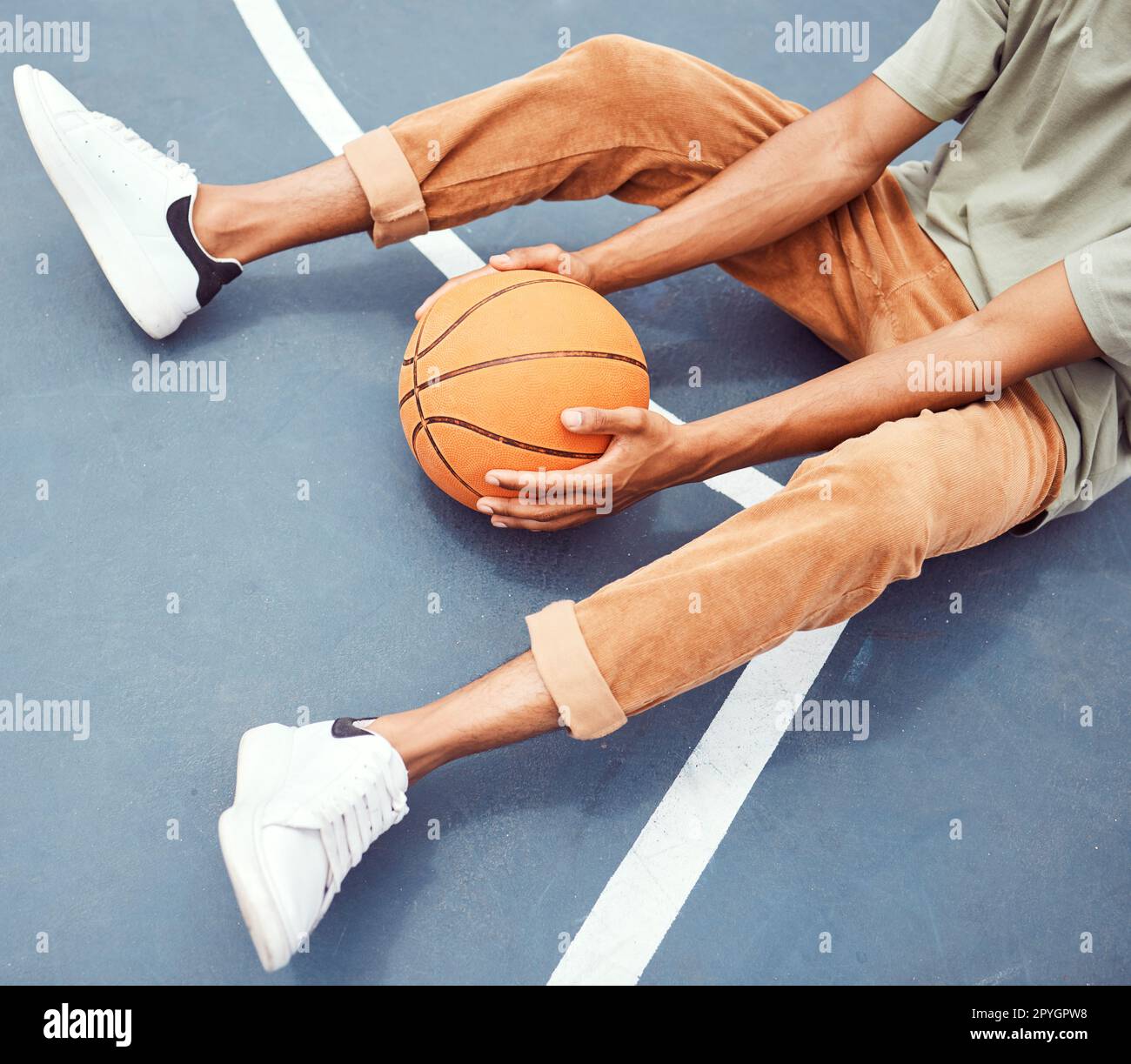 Basket-ball, mains et fitness avec un homme sportif assis seul sur un terrain, tenant une balle d'en haut. Terrain de basket-ball, pause et exercice avec un joueur de basket-ball masculin ou un athlète se reposant à l'entraînement Banque D'Images