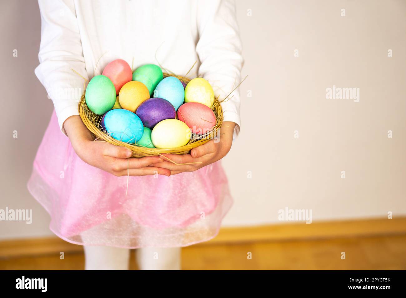 Une petite fille, de cinq ans, tenant un panier avec beaucoup d'oeufs de Pâques colorés dans ses mains. Banque D'Images