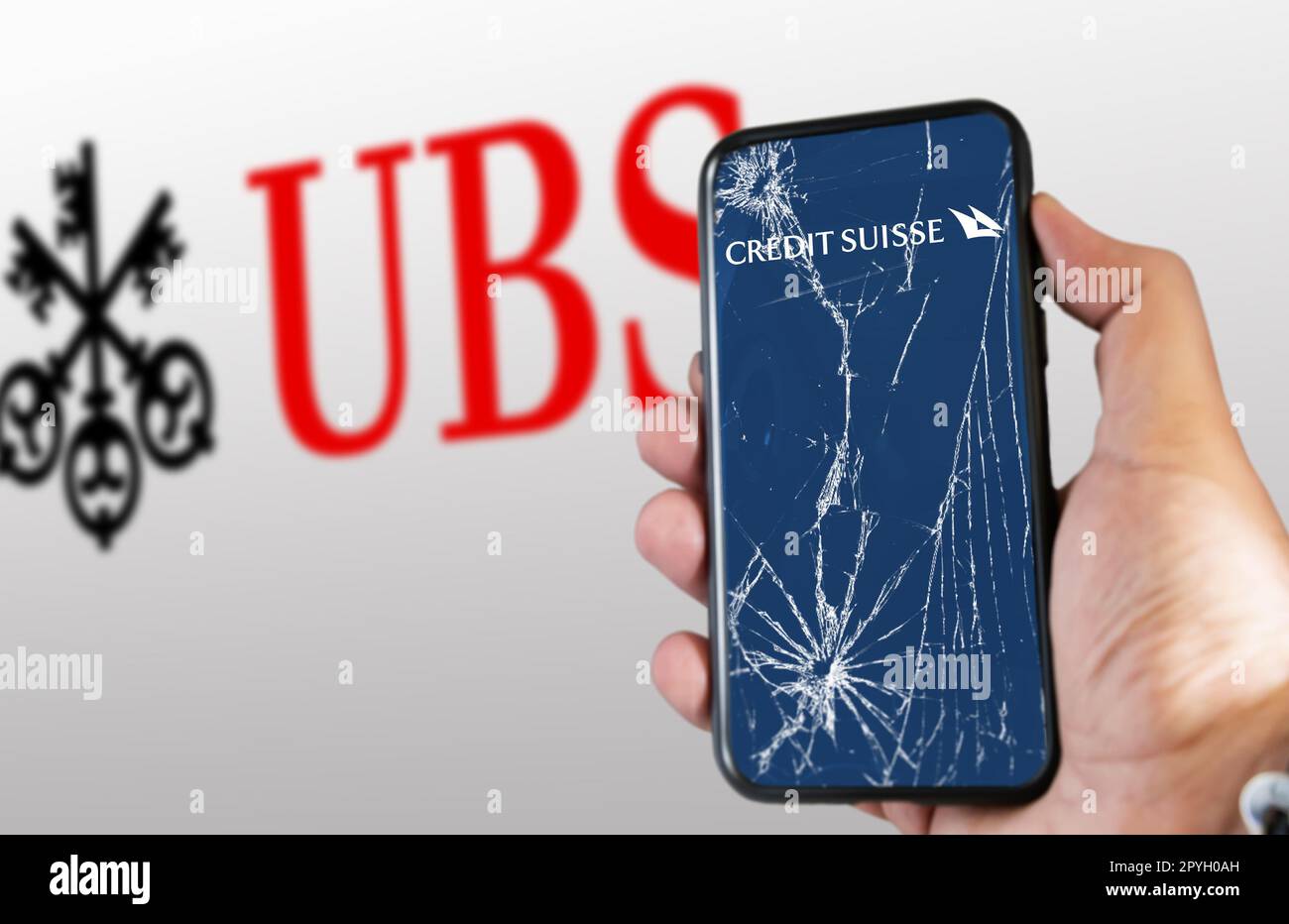 Main tenant un téléphone avec le logo du Credit Suisse sur l'écran fissuré Banque D'Images