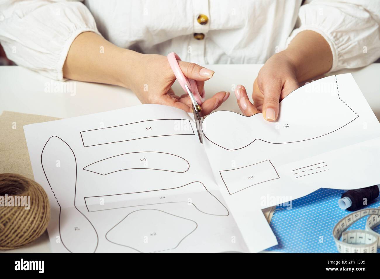 Gros plan designer féminin méconnaissable ou tailleur couper des motifs et des formes à partir de papier pour les jouets rembourrés textiles dans l'atelier Banque D'Images