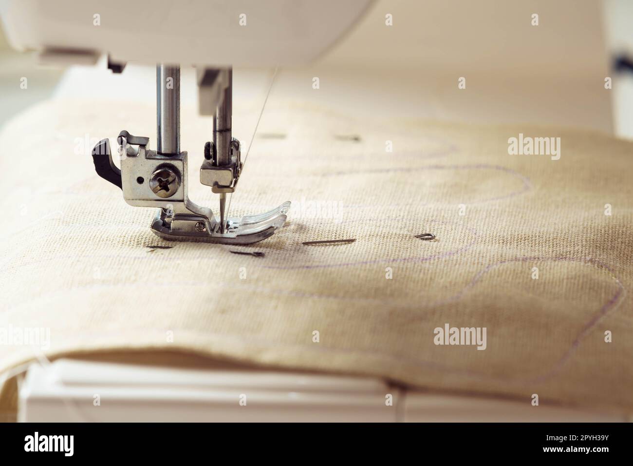 Gros plan modèle textile beige en tissu doux avec contour de couture sur la plaque d'aiguille de la machine à coudre sous la fourche de la cisaille. BRICOLAGE Banque D'Images