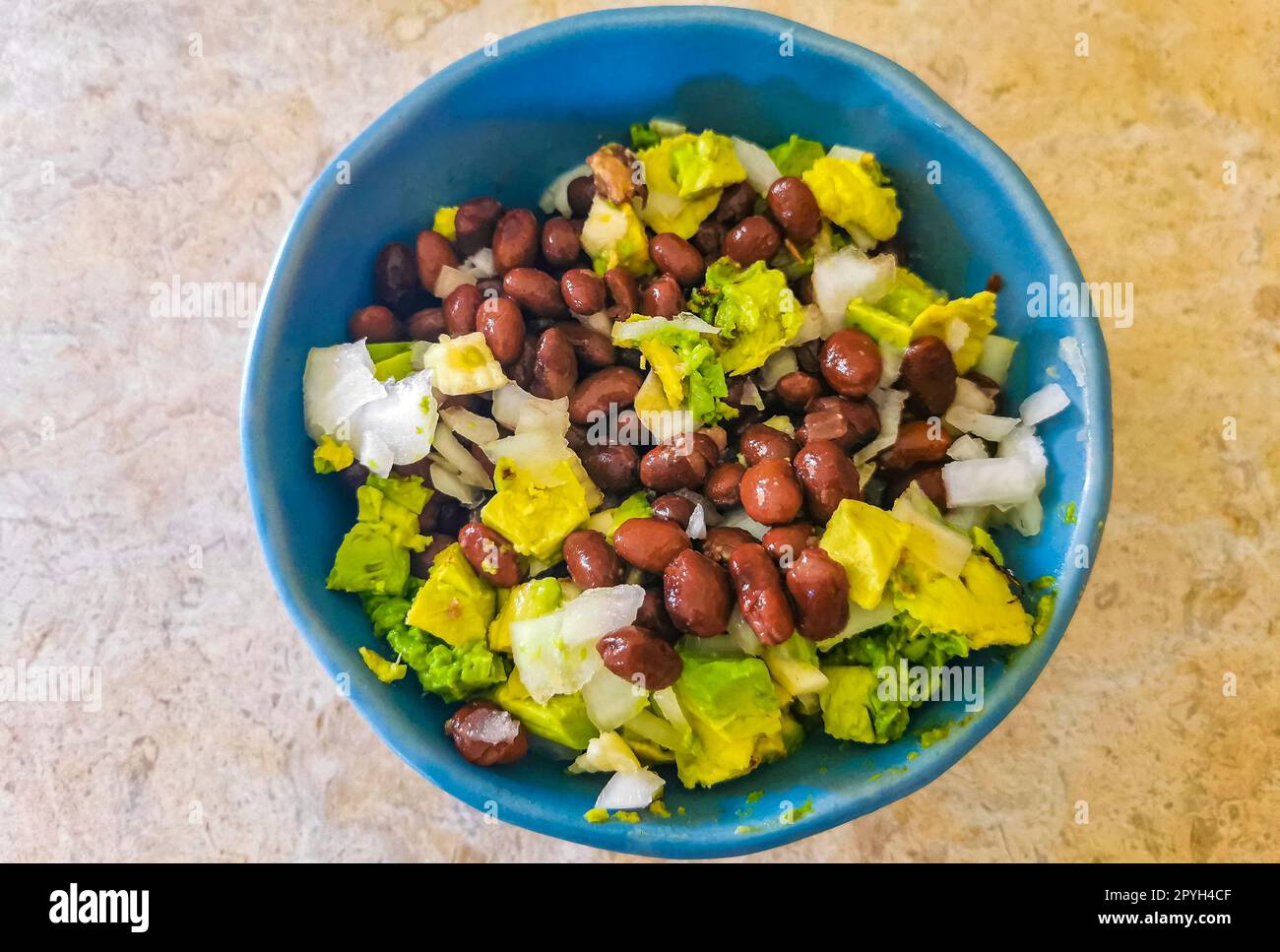 Salade de haricots, avocat et oignons maison dans un bol bleu Mexique. Banque D'Images