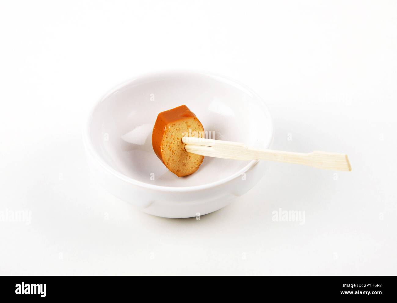 Tranche de saucisse de tofu sur une brochette en bois dans un bol en porcelaine sur fond blanc Banque D'Images