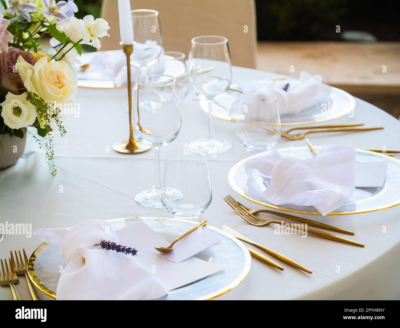 Belle décoration de mariage en plein air en ville. Bougies et fleurs séchées et accessoires avec bouquets et verres sur la table avec nappe en lin sur la table Newlywed sur la pelouse verte Banque D'Images