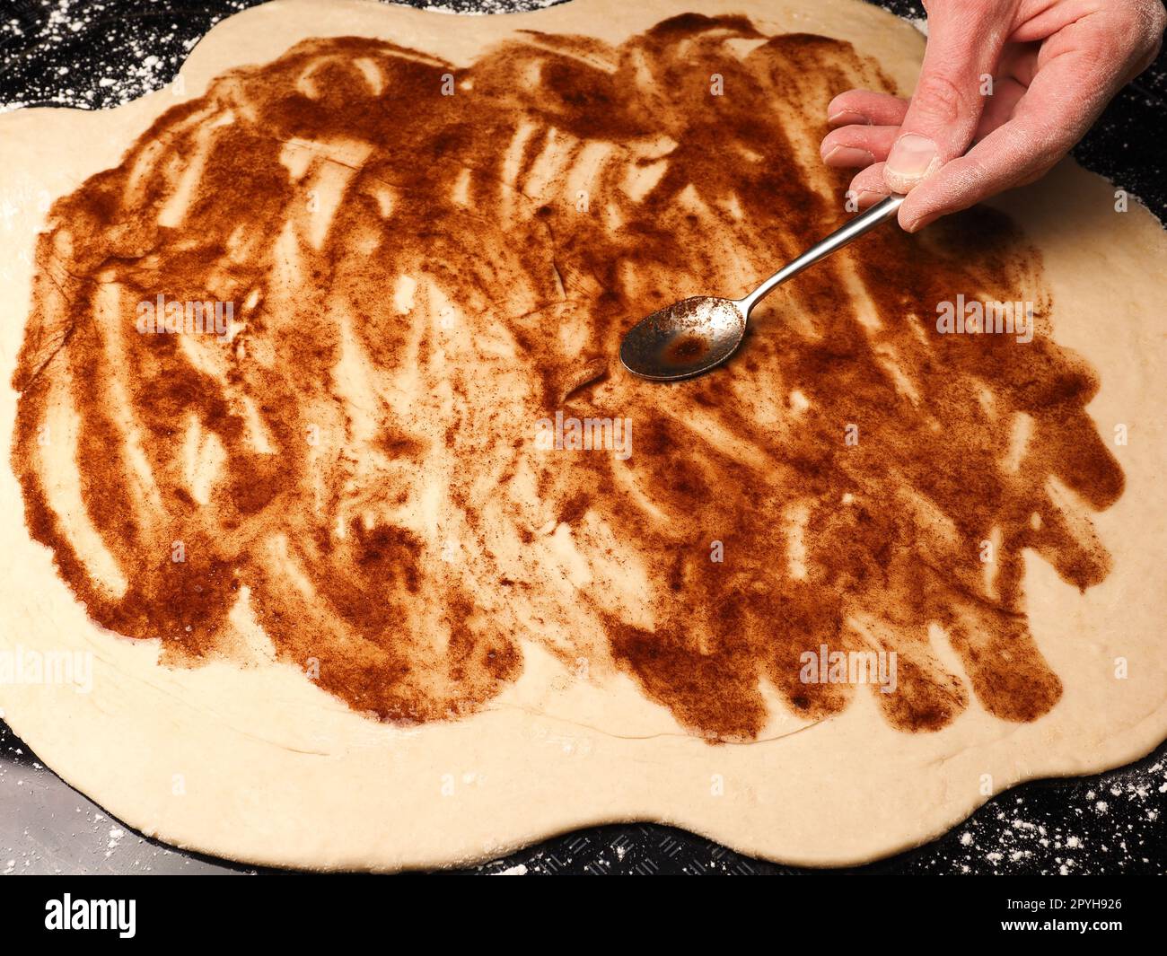 Boulonner ou cuire des pâtes à tartiner étalées de pâte à base de levure biologique avec un mélange cannelle-sucre. Banque D'Images