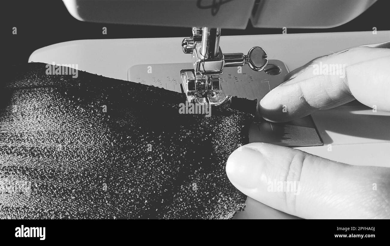 Processus de couture sur une machine à coudre moderne, gros plan. Pied de machine à coudre avec aiguille. Le tissu bleu foncé est garni d'un double emballage du bord du tissu. Lumière naturelle du soleil Banque D'Images Processus de couture sur une machine à coudre moderne, gros plan. Pied de machine à coudre avec aiguille. Le tissu bleu foncé est garni d'un double emballage du bord du tissu. Lumière naturelle du soleil Banque D'Images