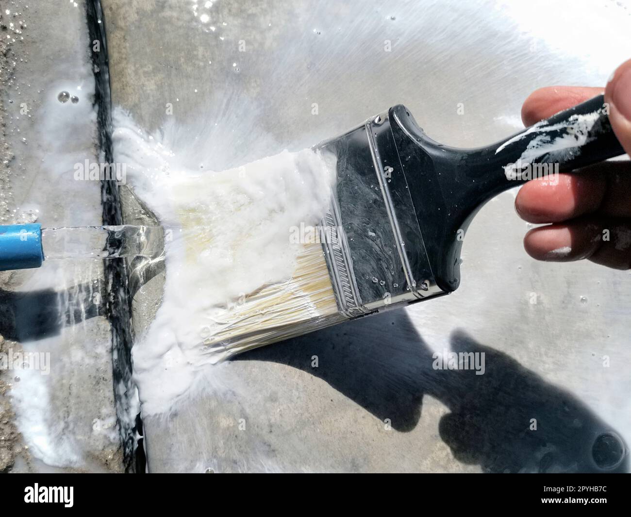 Gros plan sur les mains d'un artisan lavant une brosse de nettoyage après le travail de peinture terminé Banque D'Images