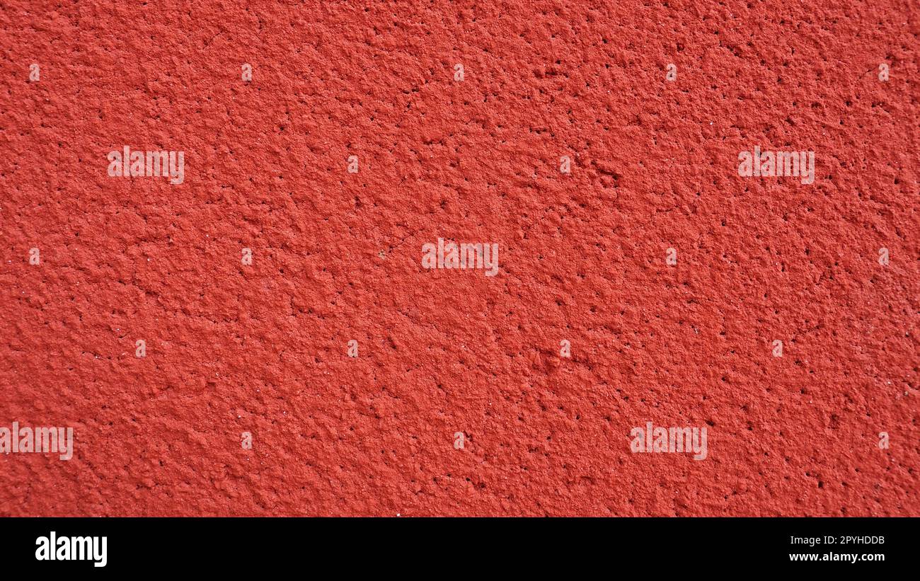 Fond, texture de plâtre de ciment de couleur rouge. Plâtrage des locaux internes et des façades externes des bâtiments. Intérieur en rouge. Banque D'Images