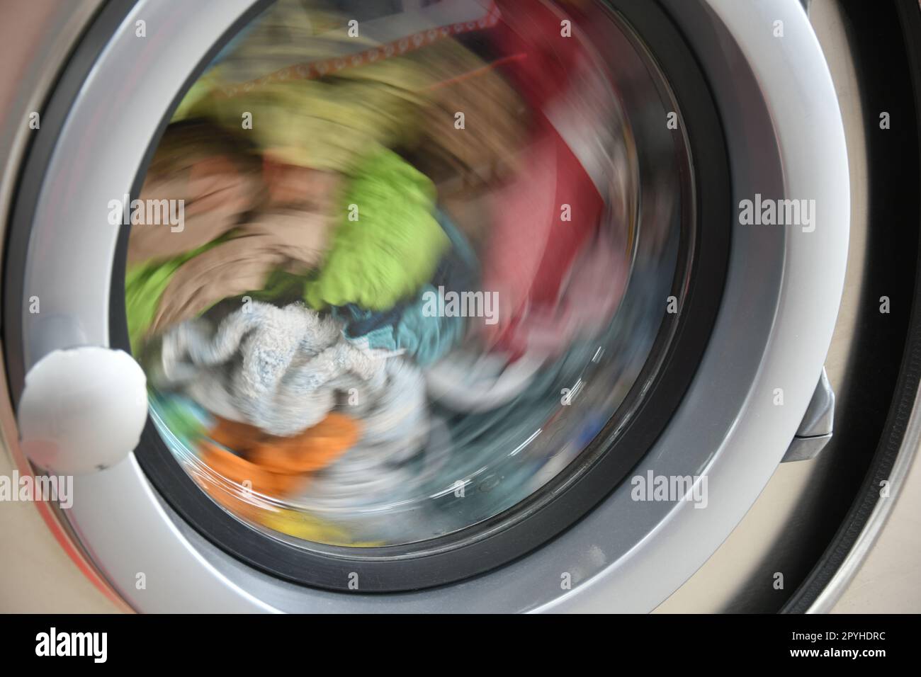 Un tambour de machine à laver en acier inoxydable rempli de linge coloré, province d'Alicante, Costa Blanca, Espagne Banque D'Images