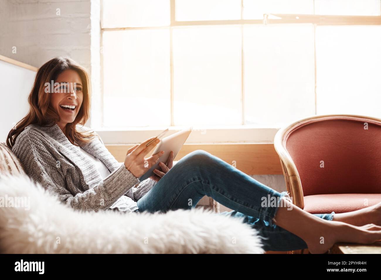 La commodité et le confort font de ce client un heureux. une jeune femme attrayante utilisant une tablette numérique et une carte de crédit sur le canapé à la maison. Banque D'Images
