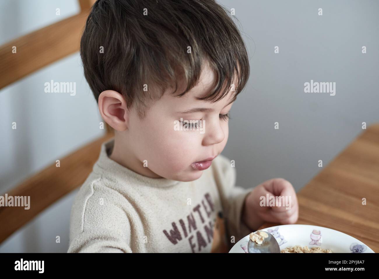 un petit garçon mange des flocons d'avoine pour le petit-déjeuner dans la cuisine Banque D'Images