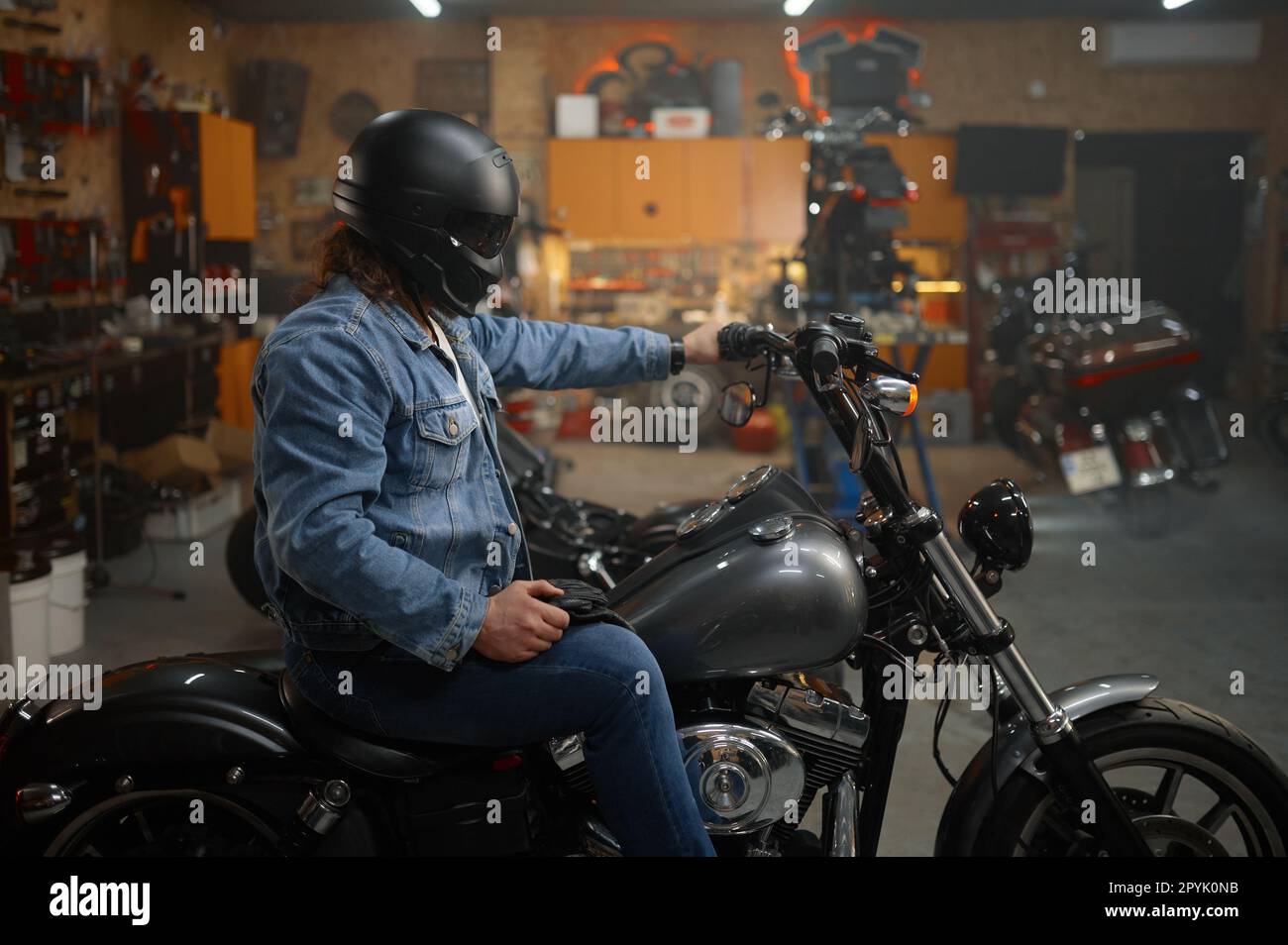 Motard dans un casque de protection assis sur une moto qui teste un nouveau véhicule Banque D'Images